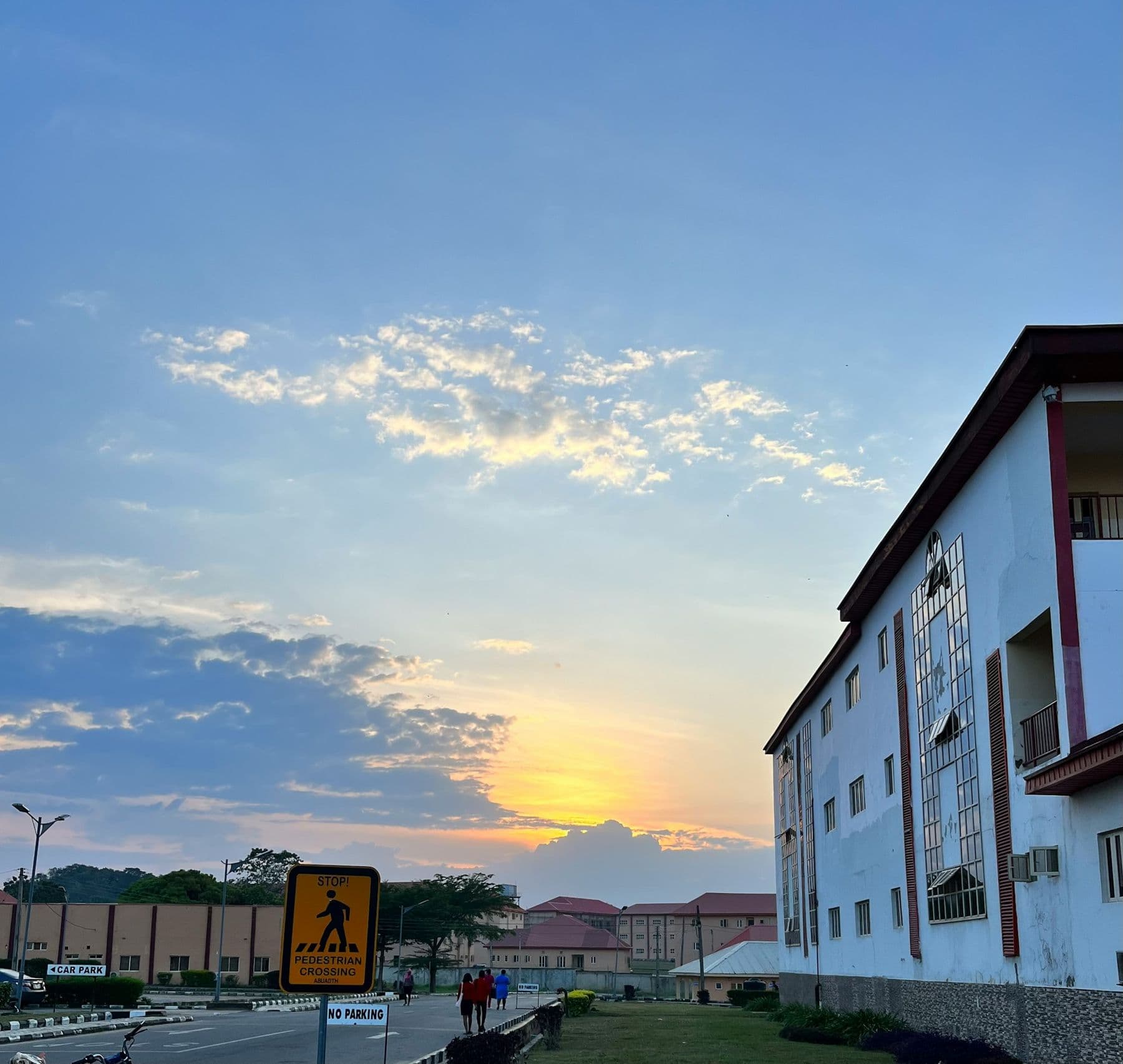 The sun low over a quiet road and buildings in a Nigerian town